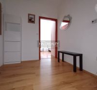 A hallway in a 2-room apartment with a wooden decor floor, simple furniture, and a mirror.