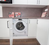 Kitchen unit with a washing machine in a studio apartment, floor with wooden decor.