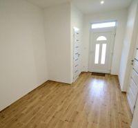 In the family house, there is a bright hallway with a wooden decor floor and light-colored doors.