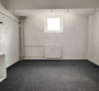 Interior of a commercial space with white walls, carpeted floor, and a shelf.
