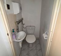Small toilet with a sink and liquid soap dispenser in commercial premises.