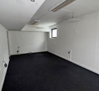 Commercial space with white walls and a window, black carpet on the floor.