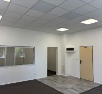Office interior with wood-patterned flooring, white walls, and a window to the hallway.