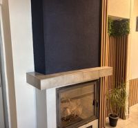 Office interior with a fireplace, flowers, and wooden wall paneling.