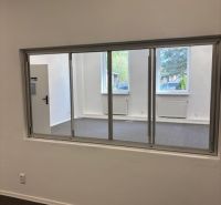 Offices with a large window, white walls, and radiators.