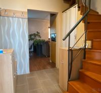 A hallway in a family house with a staircase, a patterned wall, and a floor with a wooden decor.