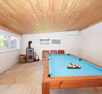 Game room in a family house with a pool table and a wood-burning fireplace.