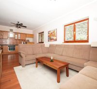 Living room in a family house with a sofa, wooden table, and kitchen in the background.