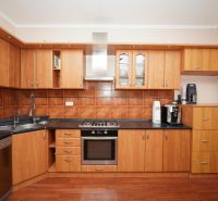 A kitchen in a family house with wooden decor and rustic tiles.