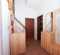 A hallway in a family house with shelves, a mirror, and stairs, with a wooden decor floor.