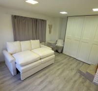 Living room in a family house with a white sofa and a floor with a wooden decor.