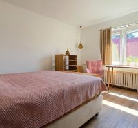 A bedroom in a family house with a bed, a chair, and a wooden decor floor.