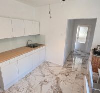 A bright kitchen in a family house with white cabinets and a marble floor.