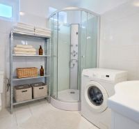 Bathroom of a family house with a shower, washing machine, and a towel rack.