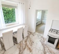 Dining room with a white table, stove, and stone floor in a family house.