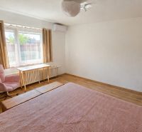 A bedroom in a family house with a wooden decor floor and light furnishings.