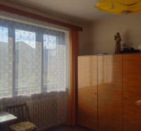 A room in a family house with a wooden wardrobe and a window with a lace curtain.