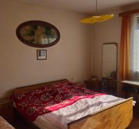 Bedroom in a family house with a bed, nightstands, a window, and a mirror.