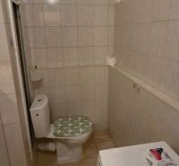 A bathroom in a studio apartment with tiles and a washing machine.