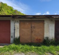 Garages on Dlha Street in Prievidza with a rusty gate and greenery around.