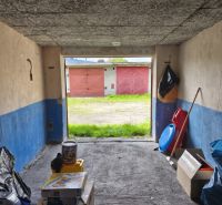 In the garage, there are stored boxes and toys, the background shows garages on Dlhá Street in Prievidza.