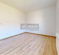 A studio apartment with white walls and a wood-patterned floor.