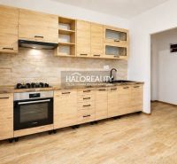 A kitchenette in a studio apartment with a wood-patterned floor and built-in appliances.