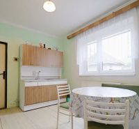 A kitchen in a family house with a dining table, chairs, and a light floor.