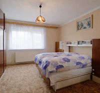 A bedroom in a family house with carpeted flooring and wooden furniture.