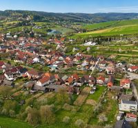 An aerial view of family houses in Horné Súčany surrounded by green fields and hills.