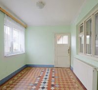 Interior of a family house with tiled floors and pastel walls, with light streaming through the windows.