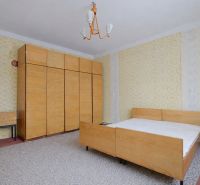 A bedroom in a family house with wallpaper, wooden furniture, and a gray carpet.