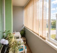 A balcony in a 4-room apartment with flowers and seating, overlooking Turňa nad Bodvou.