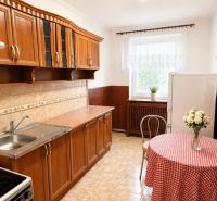 A kitchen in a 4-room apartment with wooden cabinets and tiles, complemented by a dining table.