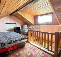 Attic room with wooden decor, bed, and wallpaper, illuminated by a window.