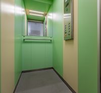 Green interior of an elevator in a 2-room apartment with a control panel.