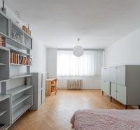 A room with shelves and a bed on the floor with a wooden decor in a 2-room apartment.