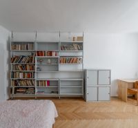 Living room in a 2-room apartment with a bookshelf, a desk, and a wooden decor floor.