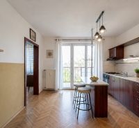 A kitchen in a 2-room apartment with a bar counter and a wooden decor floor.