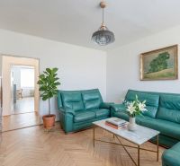 Living room in a two-room apartment with leather sofas and a table, wooden decor flooring.