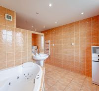 A bathroom in a 2-room apartment with a hot tub and beige tiles.