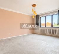 Spacious living room of a family house with a large window and radiator, beige walls, pendant lights.