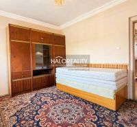 A room with a carpet and furniture in a family house, the door leads to the hallway.