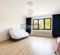 Living room of a family house with a wood-patterned floor and a large window.