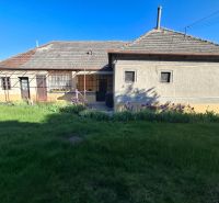 A family house in Tvrdošovce with a lawn and a flower bed in front of the building.