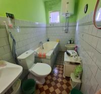 Bathroom with a bathtub, toilet, and sink in a family house with colorful walls.