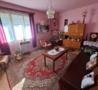 Living room of a family house with carpet and furniture, pink walls and decorations.