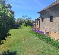 A family house in Tvrdošovce with a front garden and blooming flowers on the lawn.