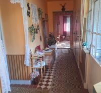 A narrow corridor with carpet, wooden decor, and curtains in a family house.