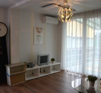Living room in a family house with a TV, clock, and wooden decor flooring.